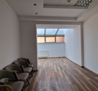 Interior of commercial premises with wood-patterned flooring and chairs by the wall.