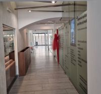Interior of commercial premises with a long corridor space, glass walls, and a light floor.