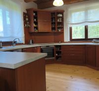 A kitchen in a family house with dark wood cabinets and a wood-patterned floor.