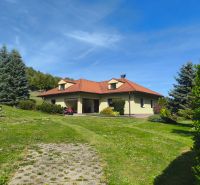 A family house in Trebostovo with a red roof, surrounded by a green lawn and trees.