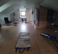 Attic room in a family house with a wooden decor floor and exercise equipment.