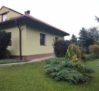 A family house in Trebostovo with a landscaped garden and wooden roof details.