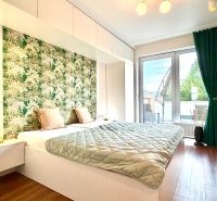 A bedroom in a three-room apartment with a wooden decor floor and a green curtain.