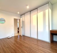 A room in a 3-room apartment with a wooden decor floor, a built-in wardrobe, and a mirror.