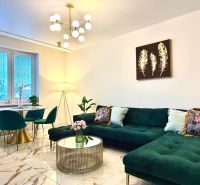 Living room in a 3-room apartment with a striking green sofa and marble flooring.