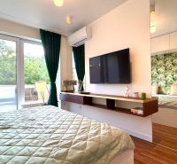 Bedroom in a 3-room apartment with large windows, green curtains, and a wooden decor floor.