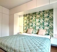 Bedroom in a 3-room apartment with a wooden decor floor and green wallpaper.
