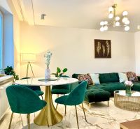 Living room in a 3-room apartment, green sofa, marble table, striking light fixture.