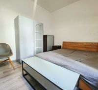 Bedroom in a 2-room apartment with a wooden bed, wardrobe, and chair.