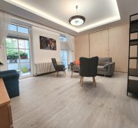 Living room in a two-room apartment, wooden decor flooring, furniture, large windows.