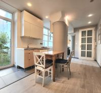 A kitchen in a 2-room apartment with a wooden table and a floor with a wooden decor.