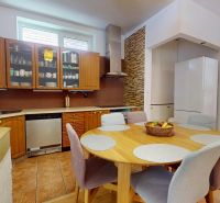 A kitchen in a family house with wooden decor kitchen cabinets and a round table.