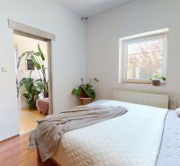 A bedroom with wood-patterned flooring, a large bed, and houseplants in a family house.