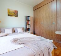 A bedroom in a family house with a large bed, a lamp, and a wardrobe with a wooden decor.