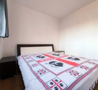 A bedroom in a 2-room apartment with a bed and a wooden decor floor.