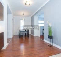 A bright dining room with wood-patterned flooring in a family house, light walls, modern lighting fixtures.