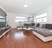 A living room in a family house with a wooden decor floor and a large corner sofa.