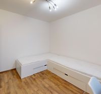 A room with two beds, white furniture, and a wood-patterned floor in a three-room apartment.