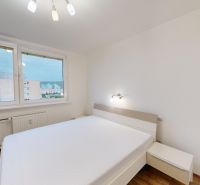 A bright bedroom with a bed, a view from the window, and a wooden decor floor in a 3-room apartment.