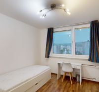 A room in a 3-room apartment with a bed, a desk, and a wooden-patterned floor.