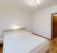 A bright bedroom with a bed, wood-decor flooring, and minimalist lighting in a three-room apartment.