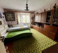 Bedroom in a family house with carpeted floor, wardrobe set, and large window.