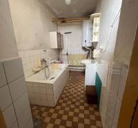 A bathroom with a bathtub in a family house, tiled with a radiator and a gas boiler.