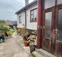 A family house in Cerová with courtyards and greenery, bordered by wooden and stone elements.