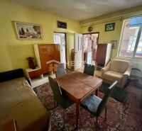 Living room of a family house with a carpet, wooden furniture, and wall paintings.