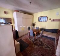 Living room with carpets, wooden decor, and simple furniture in a family house.