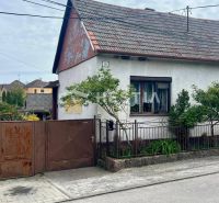 A family house in Cerová with a gate and a small garden, surrounded by greenery.