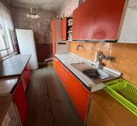 A kitchen in a family house with orange cabinets and a wood-patterned floor.