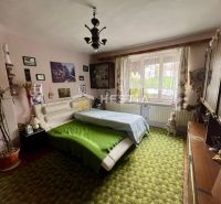 Interior of a family house with a green carpet, decorative paintings, and a large window.