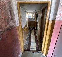 A narrow hallway with damaged walls and a tiled floor in a family house.