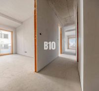 A hallway in a 3-room apartment with large windows and a concrete floor.