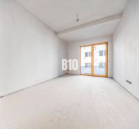 Empty room with a concrete floor and large windows in a 3-room apartment.