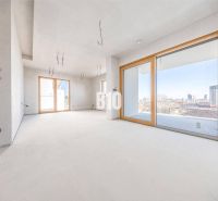Spacious bright interior in a 3-room apartment with large windows and neutral flooring.