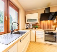 A kitchen in a family house with a wooden decor floor and wooden windows.