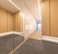 A hallway in a 3-room apartment with a wooden decor floor and a mirror.