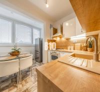 A kitchen in a 2-room apartment with a wooden decor floor and a dining area.
