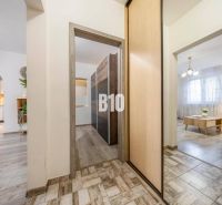 Interior of a 2-room apartment with a wooden decor floor, light furniture, and arched transitions.