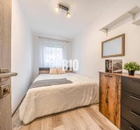 Bedroom with a bed, dresser, and wooden decor flooring in a two-room apartment.