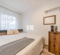 Bedroom in a two-room apartment with a bed, shelves, and a floor with a wood decor.