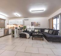 A bright living room in a family house with a kitchen and a large sofa.