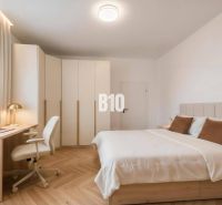Bedroom in a 4-room apartment with wood-patterned flooring, a desk, and a built-in wardrobe.