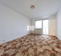 Living room in a 4-bedroom apartment with carpeted flooring and a large window.