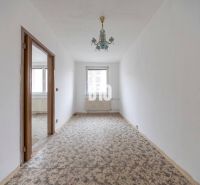 A narrow room in a 4-room apartment with a carpet and a vintage chandelier.