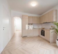 A kitchen in a 4-room apartment with a wooden decor floor and light furniture.