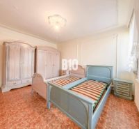 A bedroom in a family house with a wood-decor floor, beds, and wardrobes.