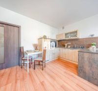 Kitchen corner in a 2-room apartment with a wooden decor floor and a dining table.